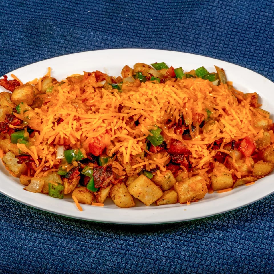 A Sunnyside Diner breakfast skillet with crispy potatoes, bacon, peppers, onions, and melted cheddar cheese.