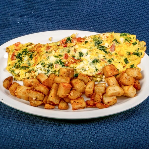 A Sunnyside Diner omelet with spinach, tomatoes, and cheese, served with crispy home fries.
